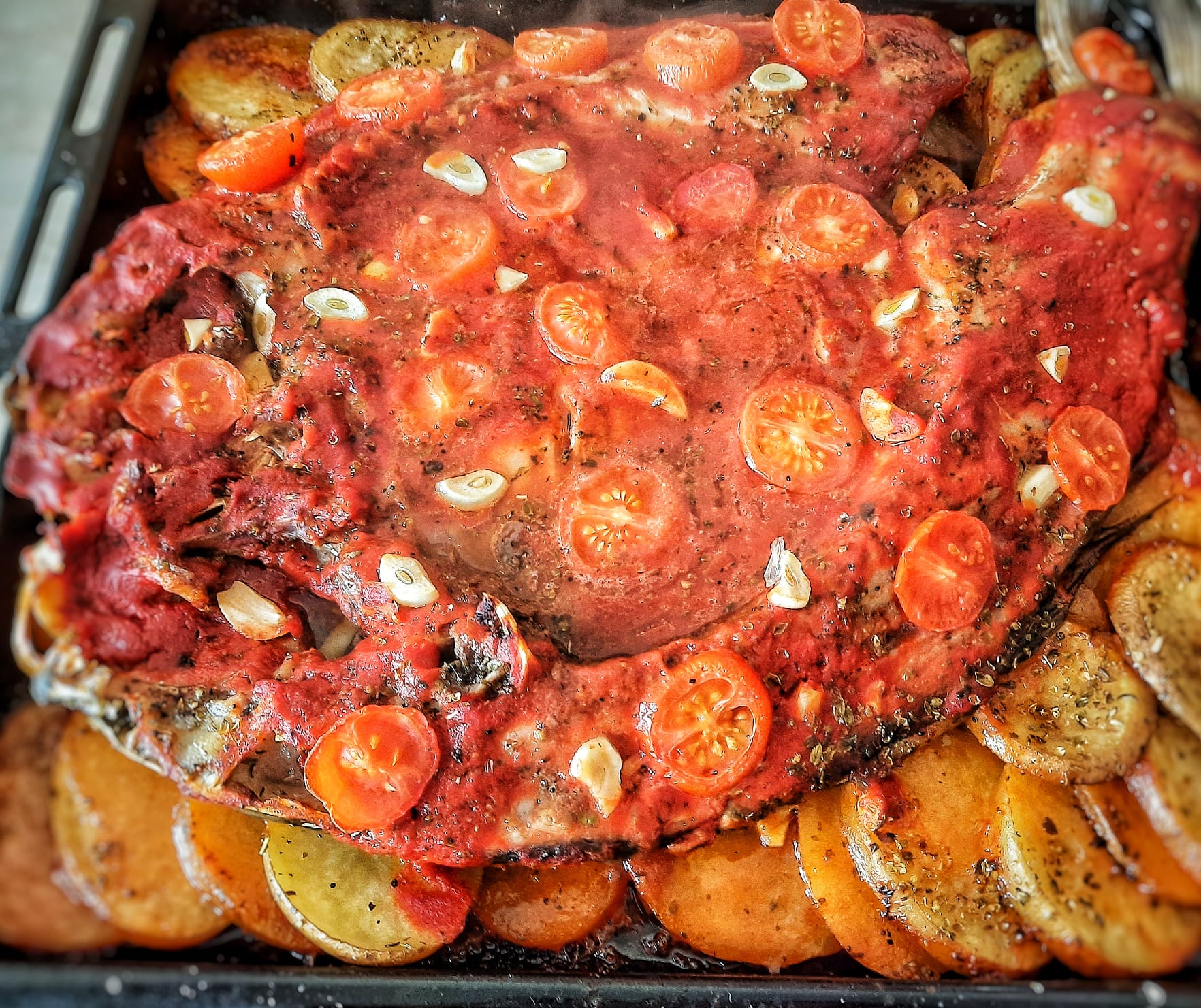Whole baked fish with tomatoes and potatoes