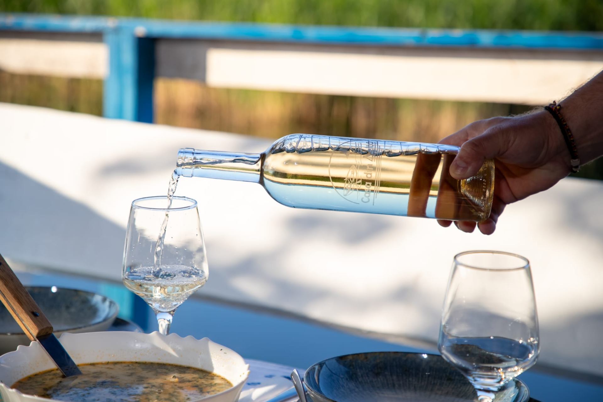 Pouring local white wine with fish soup